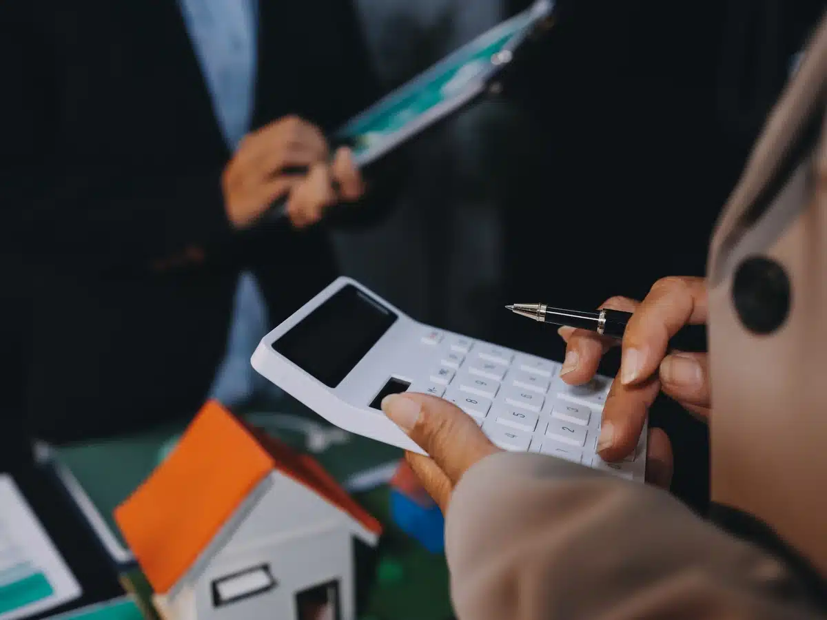 Close-up of hands using a calculator beside documents to estimate home value in Denver Colorado.